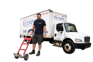 Man holding dolly with a moving truck that says Olympic Moving & Storage