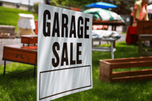 A sign for a garage sale in the grass, advertising the 'Garage Sale', representing the ultimate garage sale guide.