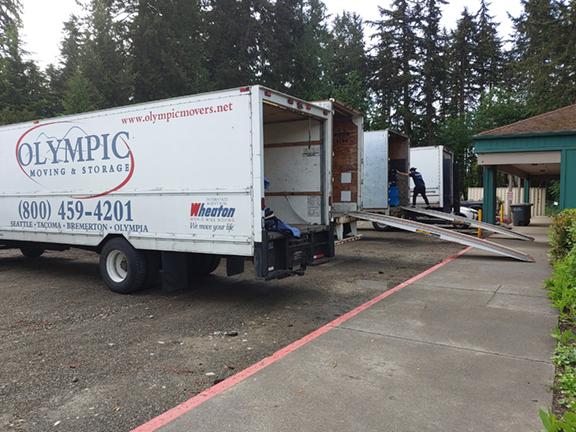 An open commercial moving truck is parked in front of an office, belonging to Federal Way movers, Olympic Moving and Storage.