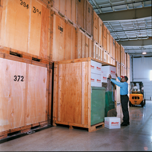 An Olympia mover standing in a warehouse at an Olympia Moving Company, surrounded by various storage options for short or long term storage solutions.