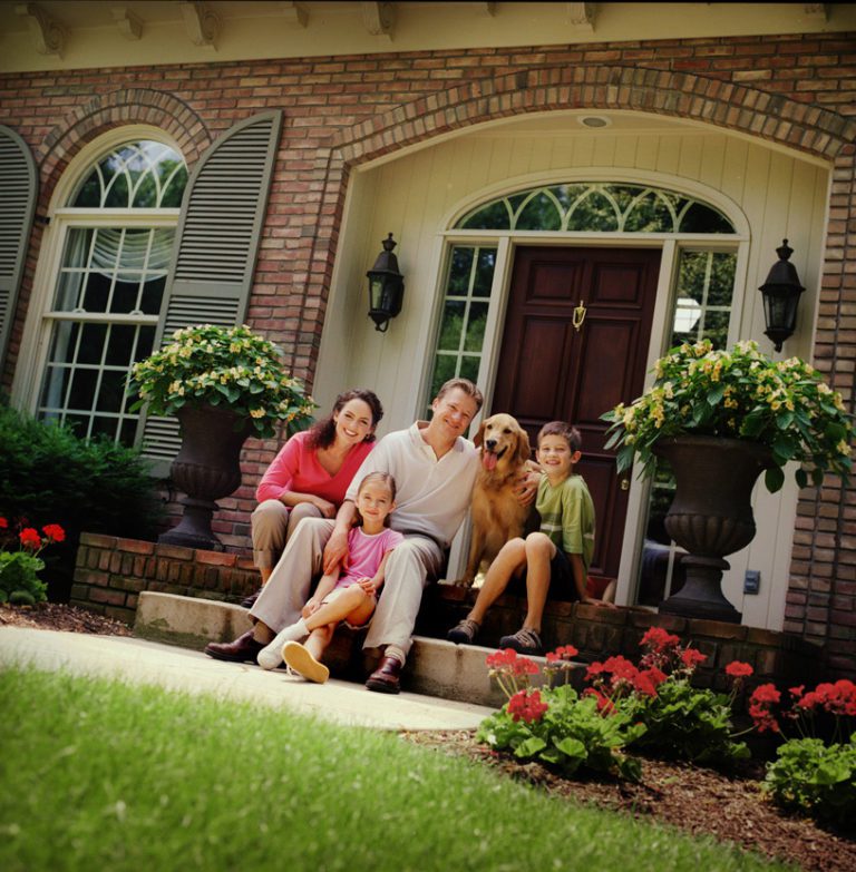 A happy family sitting on the steps of their house, enjoying the comfort of their new Federal Way home after experiencing a stress-free move with Federal Way moving company, Olympic Moving and Storage.