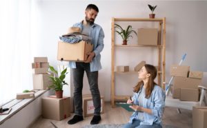 A couple carrying moving boxes into a room in Washington, while following the ultimate moving checklist.