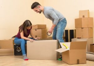 A couple moving moving boxes in an empty, Washington room, representing a guide to self packing tips.