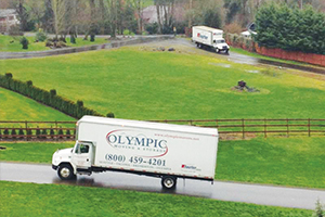 Olympic Moving & Storage's truck driving up a residential road. Olympic Moving & Storage - Tacoma, WA: Trusted Tacoma Moving Company for Local Moving.