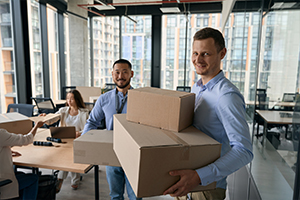 Group of employees in a Tacoma office, holding moving boxes during an office relocation. Tacoma moving company assisting with employee relocations.