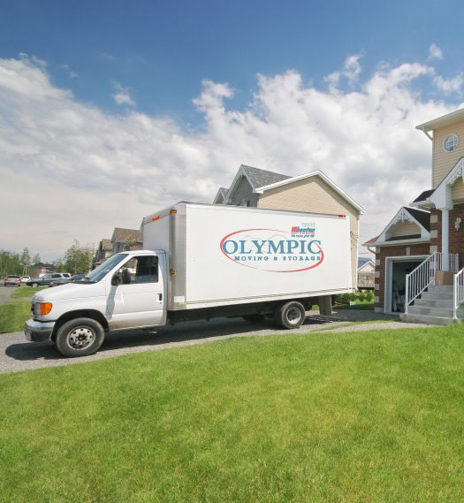 A moving truck is parked in front of a house. Services provided by Tacoma Moving Company, Olympic Moving and Storage, serving Pierce, King, Thurston, and surrounding areas.