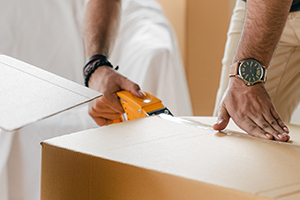 Professional, Tacoma moving company mover carefully tapes a moving box, demonstrating packing services.