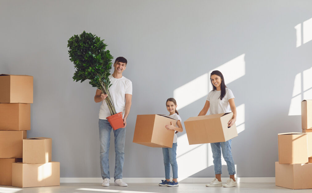 A family carrying plants and moving boxes into their new Washington home, demonstrating how to plan ahead for a spring move.