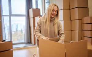 A woman packing moving boxes in a Washington apartment during winter, representing everything you need to know when moving in winter.