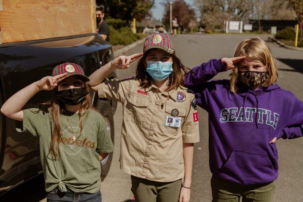 Three Boy Scouts wearing face masks and saluting, demonstrating that Olympic Moving & Storage is proud to be part of the community.